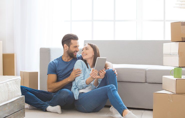 Man and Woman Sitting on Floor against Couch with Boxes